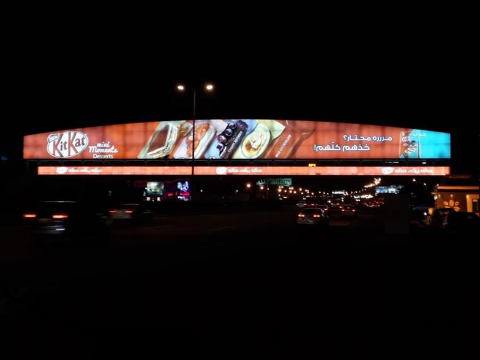 Illuminated advertising display spanning a road in KSA at night